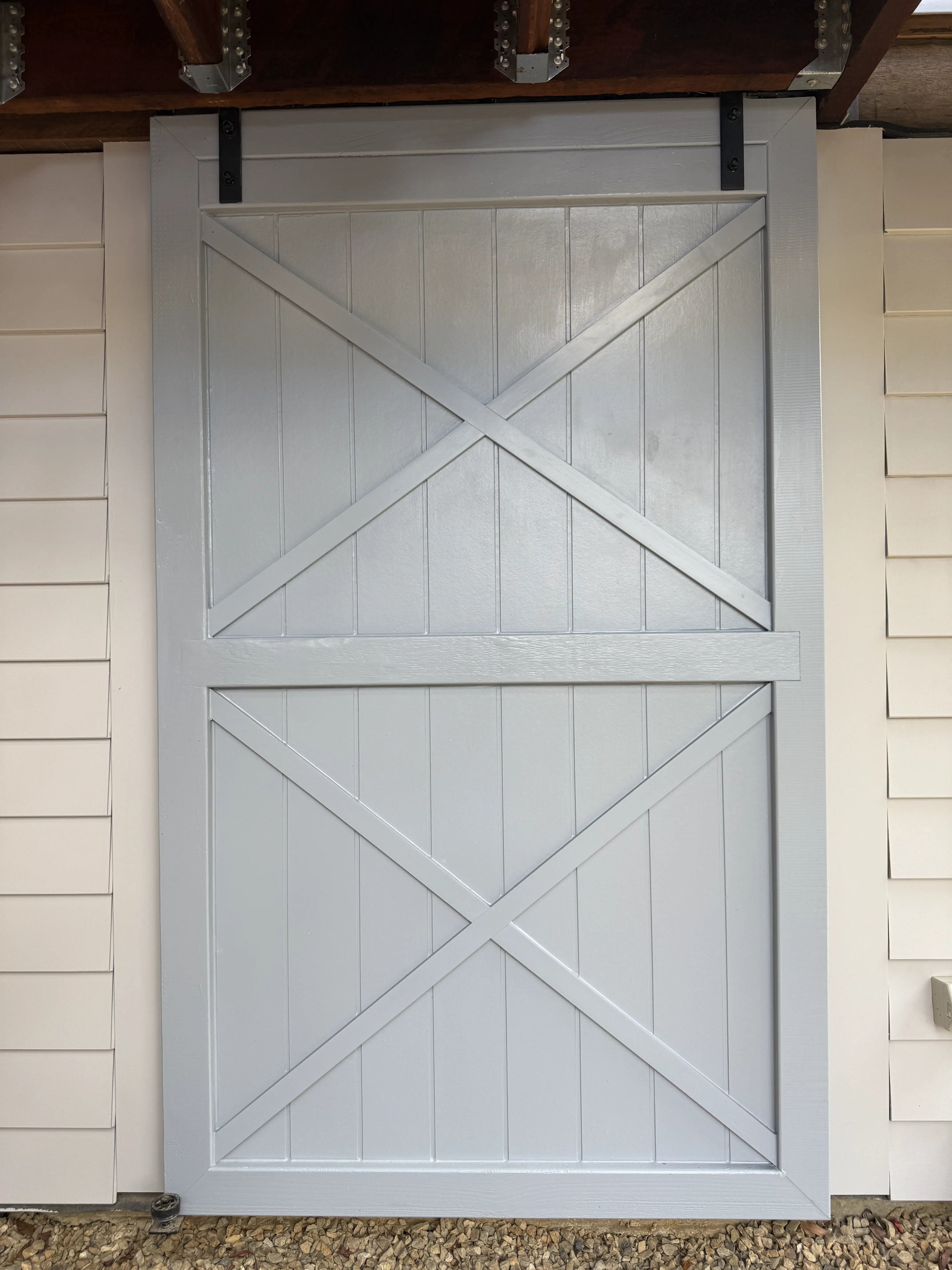 Painted barn-style door under deck structure